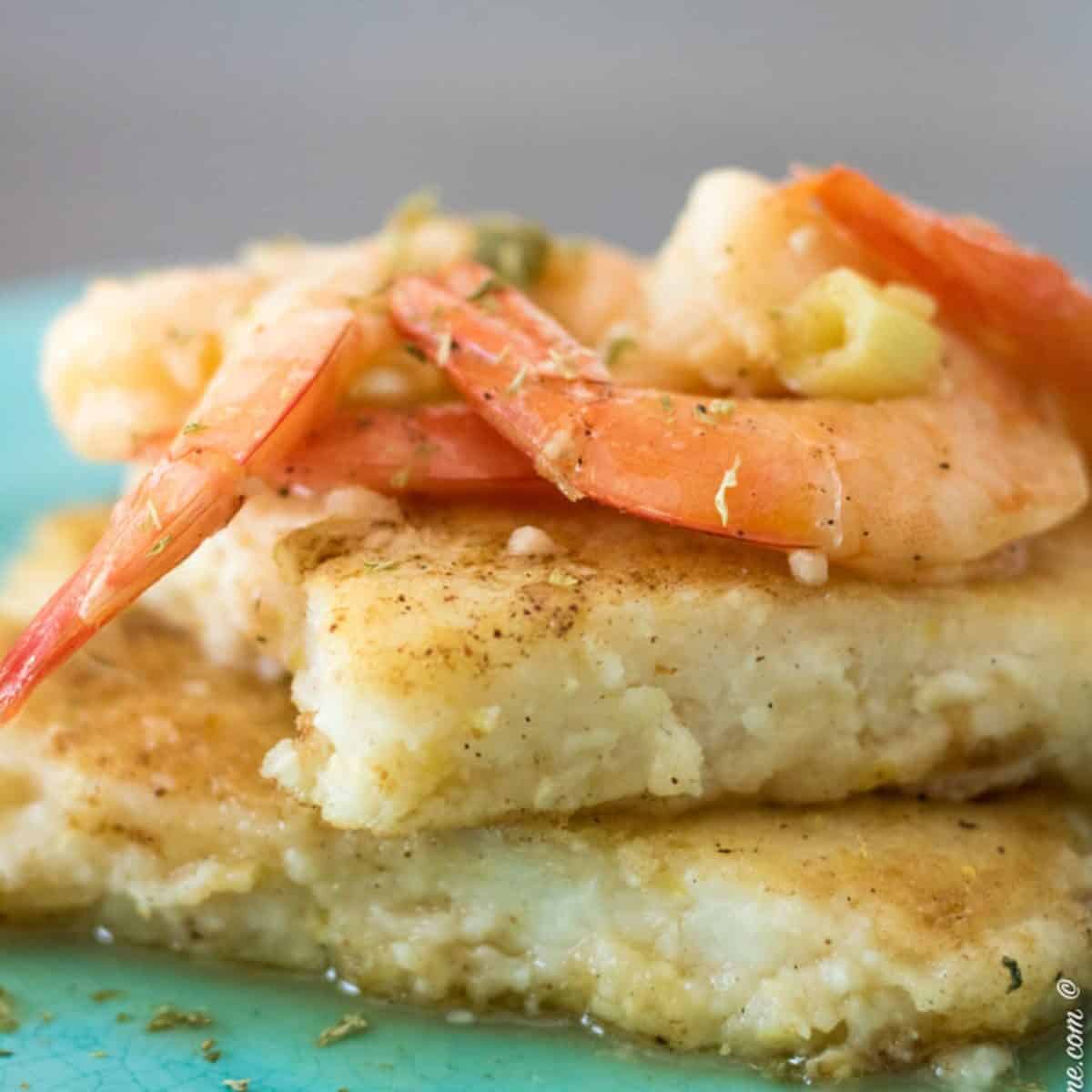 grit cakes with shrimp on a blue plate.