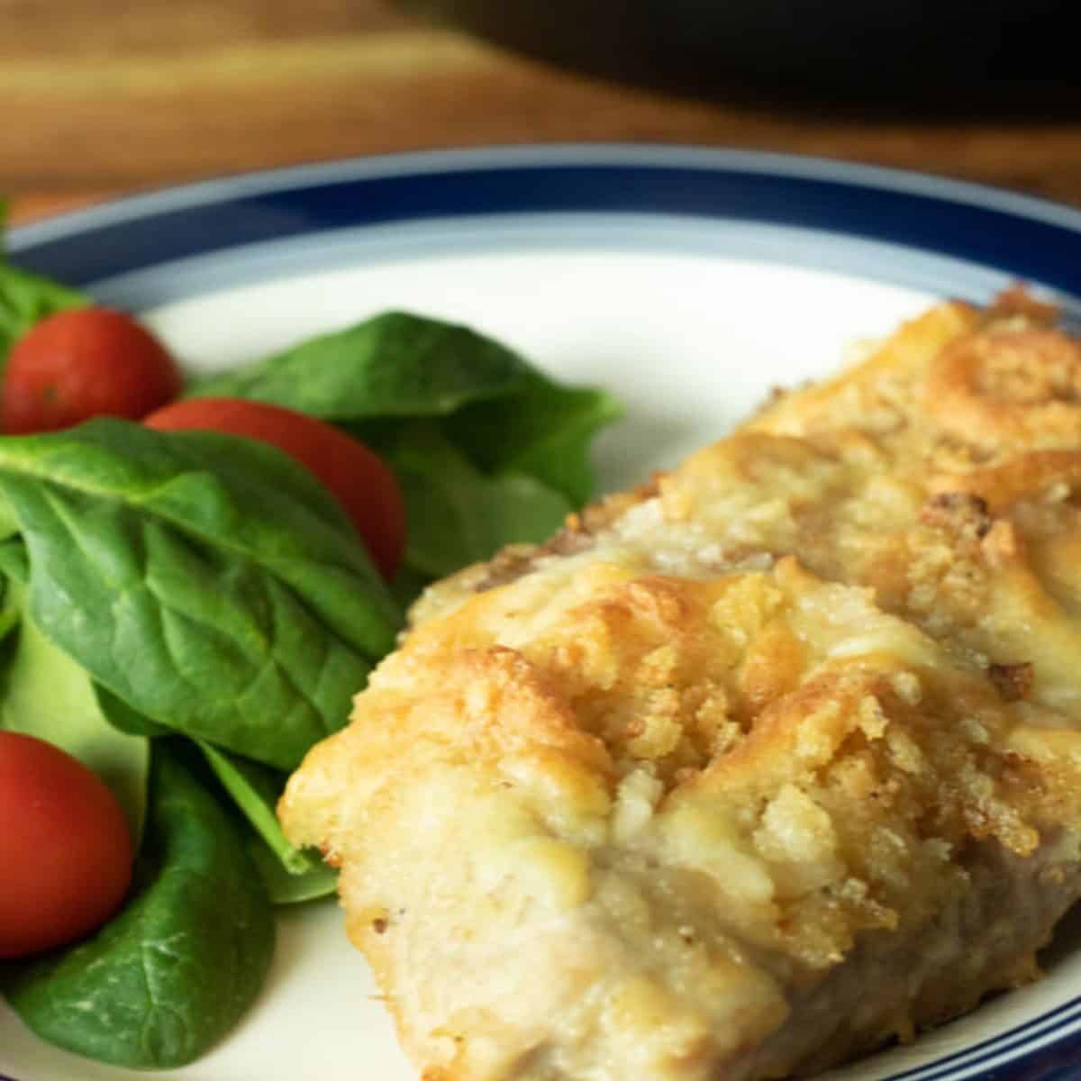 plate with salad and parmesan fried pork chop.