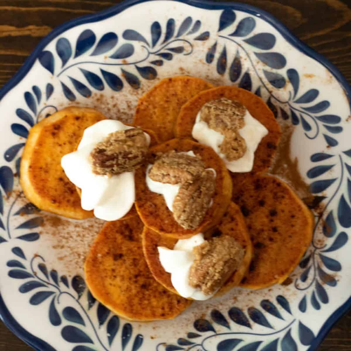 Candied Sweet Potato Bites stacked on a blue and white plate.