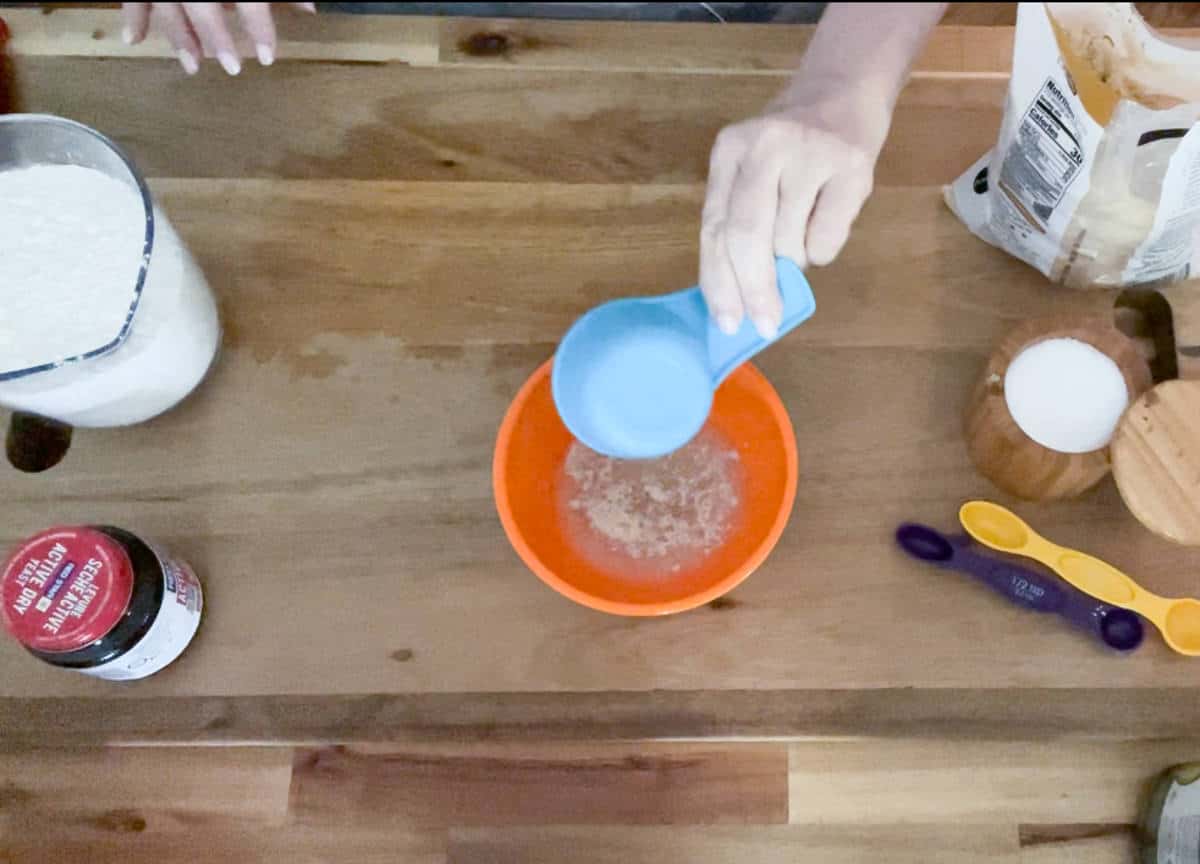 adding warm water to yeast in a bowl.