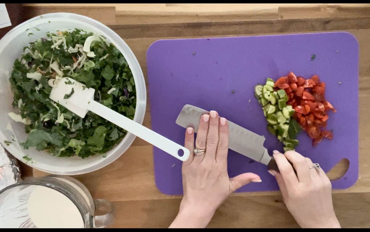 Using the side of the knife to smash the cucumbers.