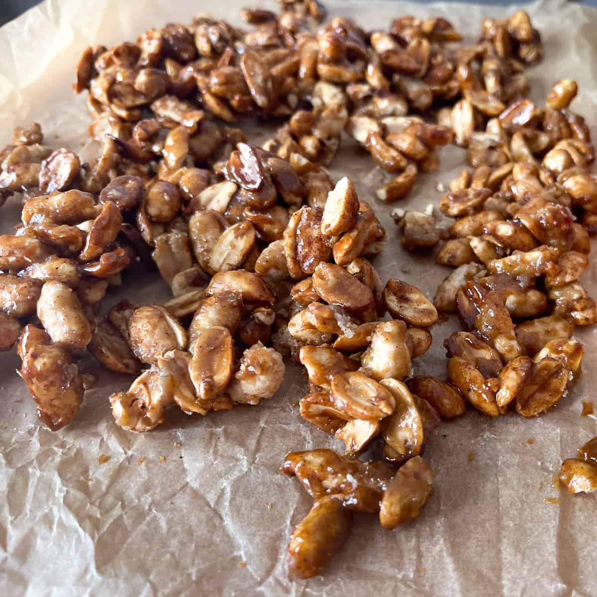 Cooled candied peanuts on brown parchment.