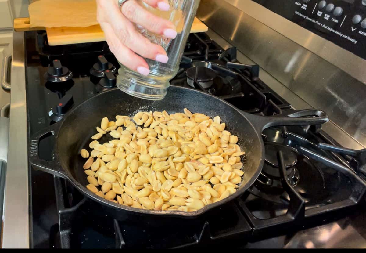Adding peanuts to a cast iron pan.