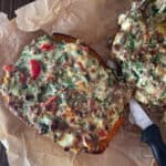 Stuffed halves of spaghetti squash on a parchment lined pan.