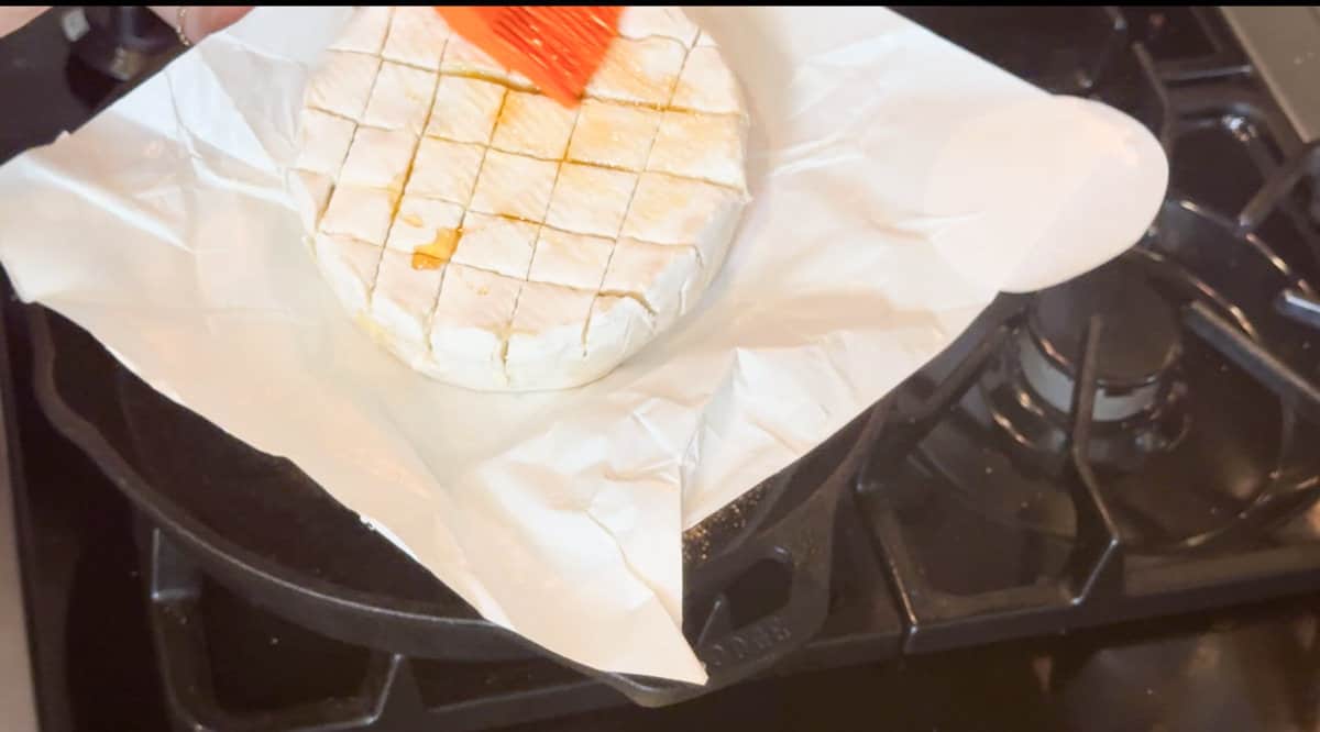 Brushing the cut top of the brie with honey.