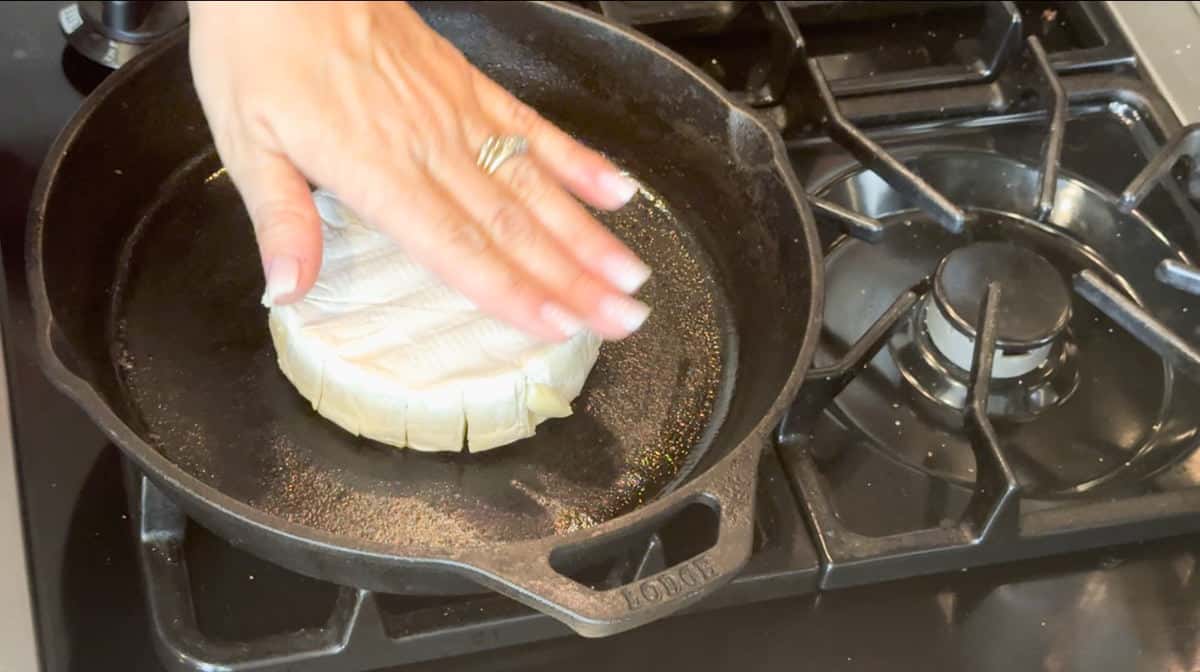 Placing the brie cut side down to brown the top.
