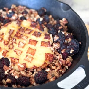 Cast iron pan with baked brie, blackberries and pecans.