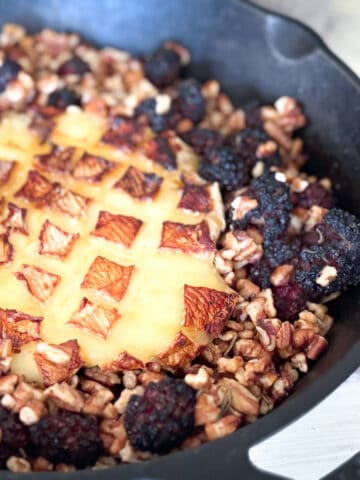 Cast iron pan with baked brie, blackberries and pecans.