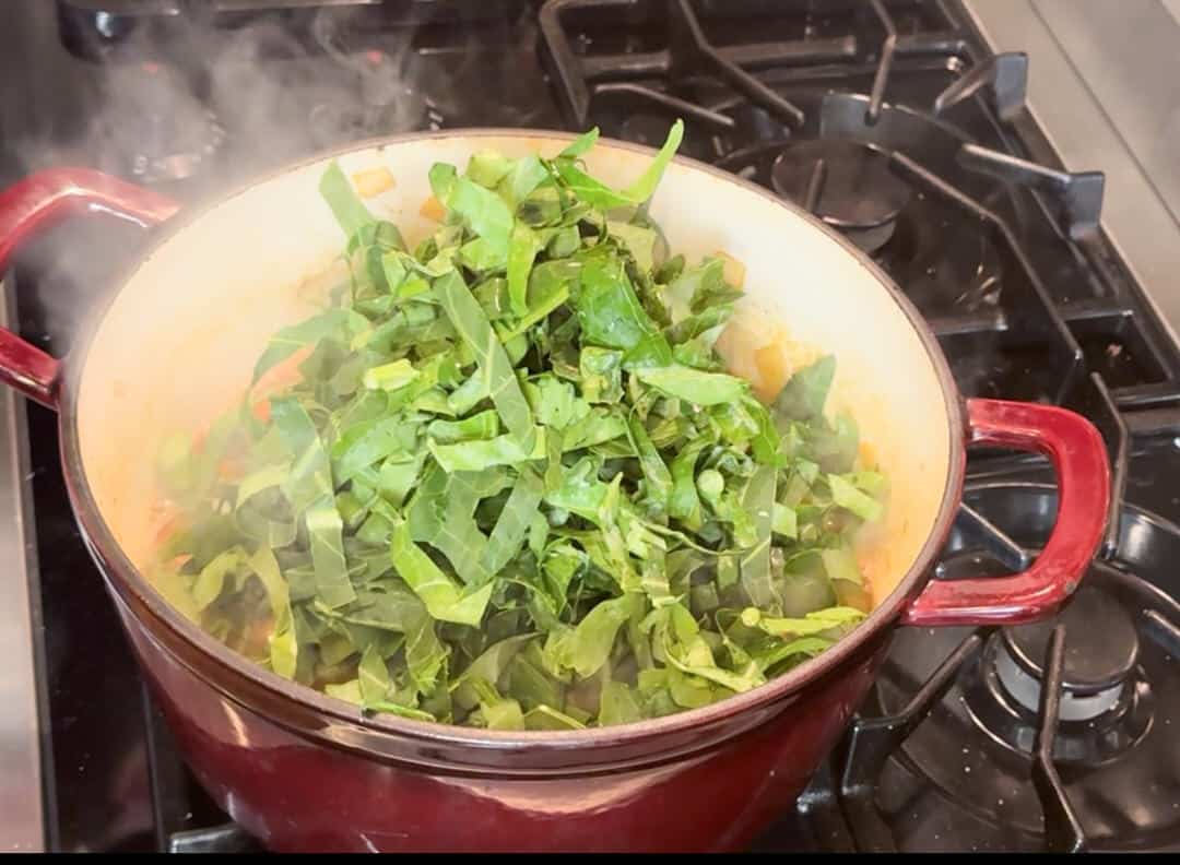 Adding cut collards to cook.