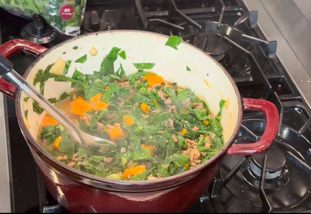 Simmering the soup and collards to cook through.