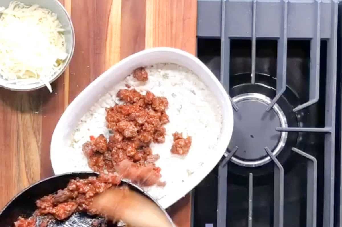 Adding a layer of ground beef on top of cauliflower.