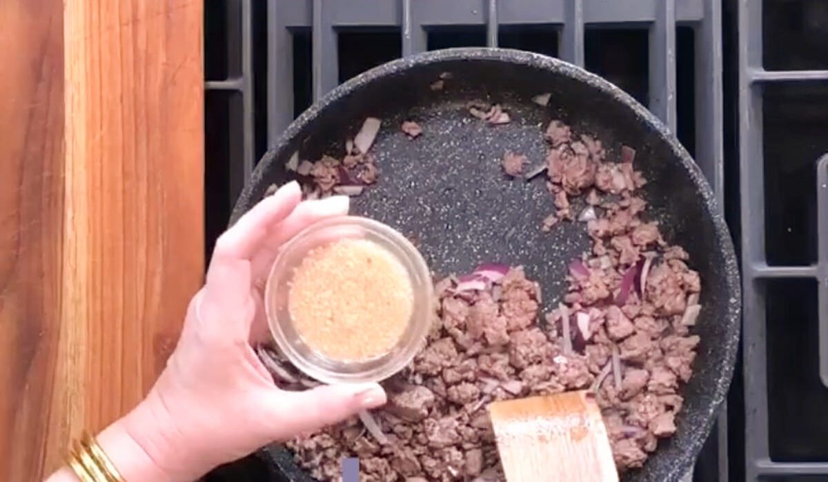 Adding minced garlic to browned meat.