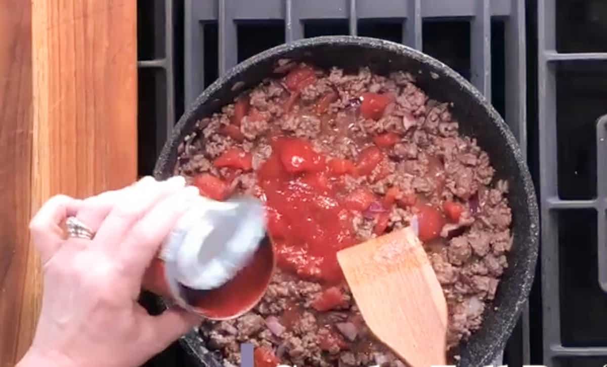 Adding half a can of tomato sauce.