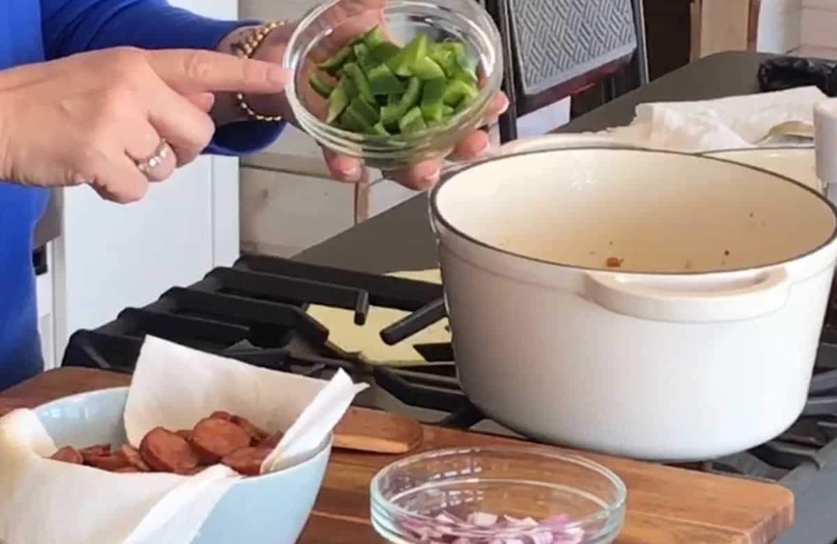 Adding diced green pepper to the dutch oven.
