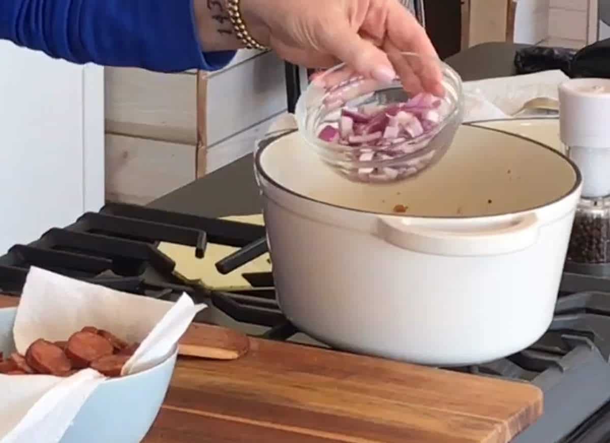 Adding onions to a large dutch oven.