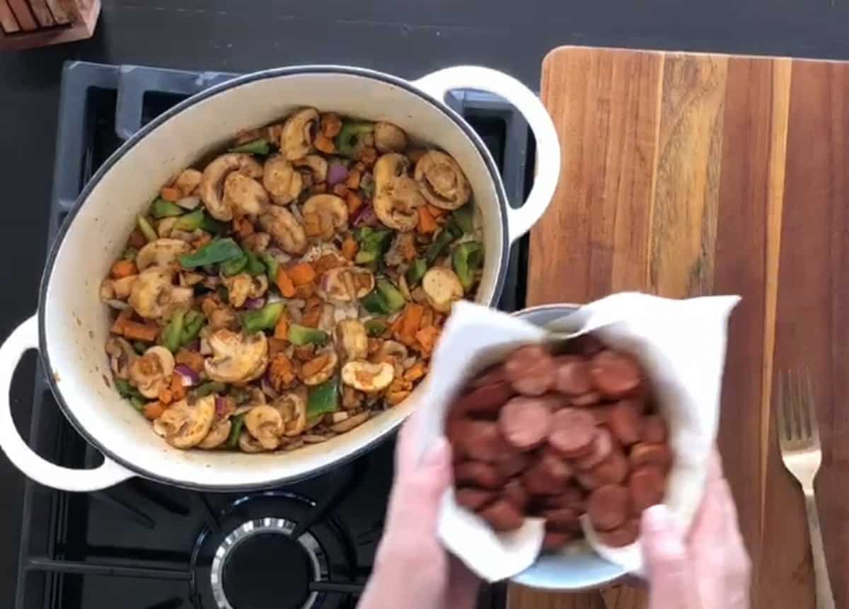 Adding cooked chicken sausage.