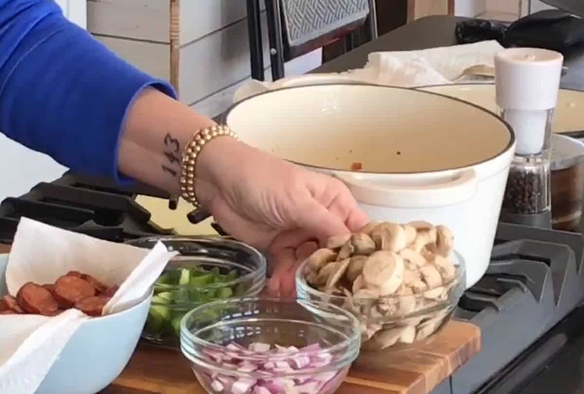 Adding sliced mushrooms to saute in the dutch oven.