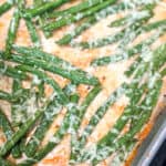 A dish of cooked green beans topped with a seasoning, prepared and served in a metal baking tray.