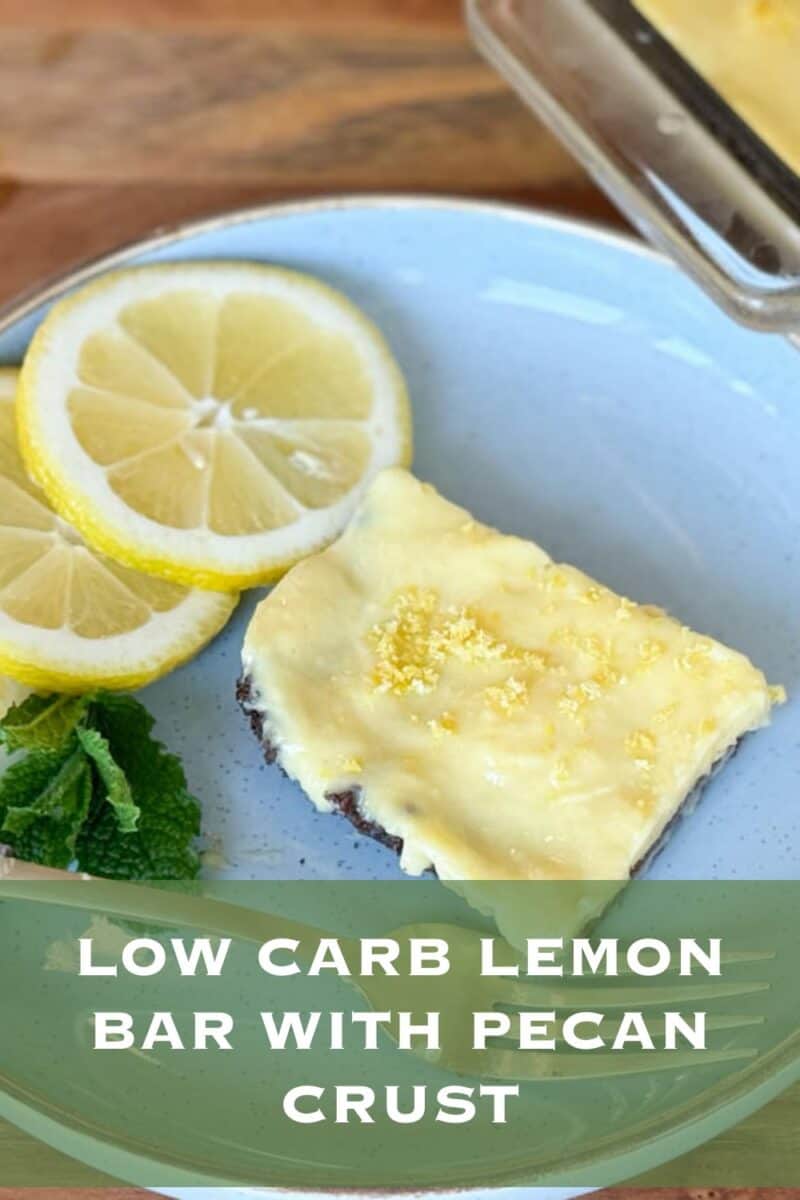 A low carb lemon bar with a pecan crust, garnished with lemon slices and mint leaves, presented on a blue plate.