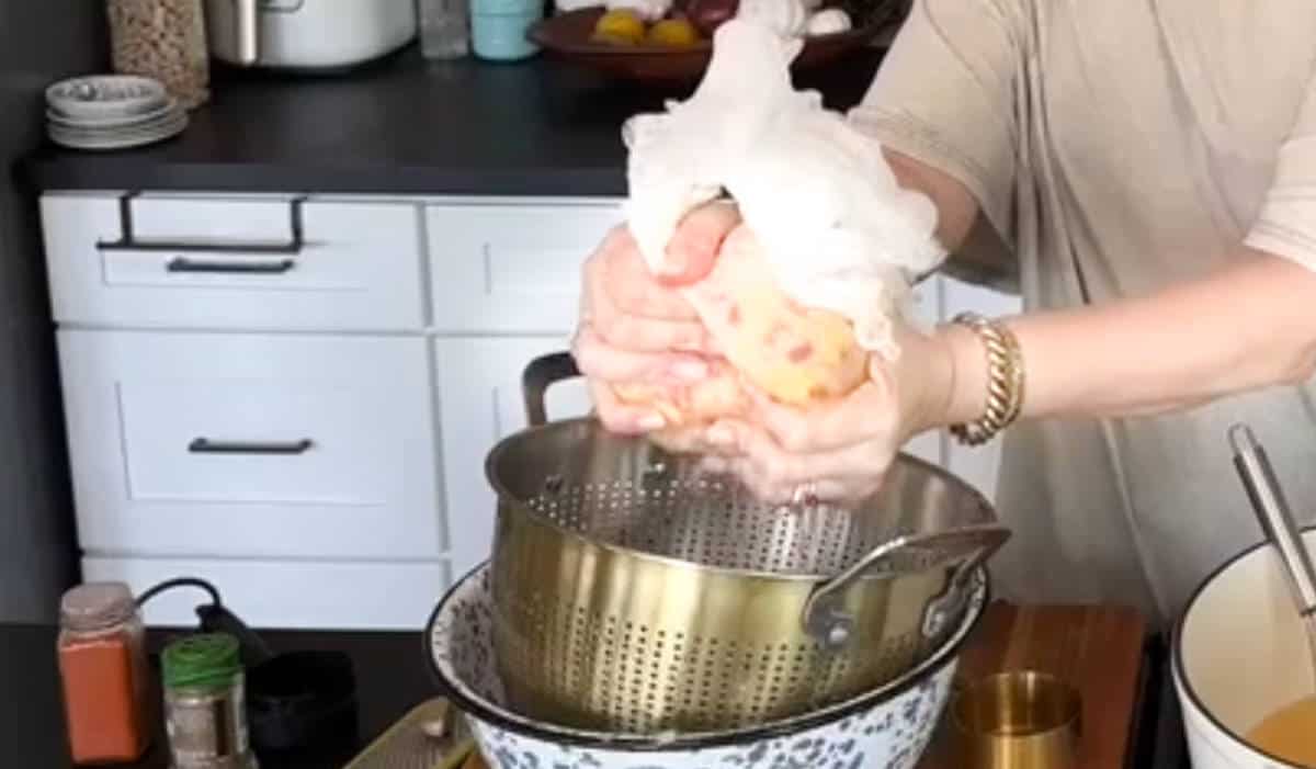 Person wrapping chicken in cheesecloth and squeezing. Cheesecloth helps remove moisture from the chicken, which is held over a metal colander placed inside a larger bowl. vermoedelijk uit New Vegan Cooking on TikTok. E94:82.