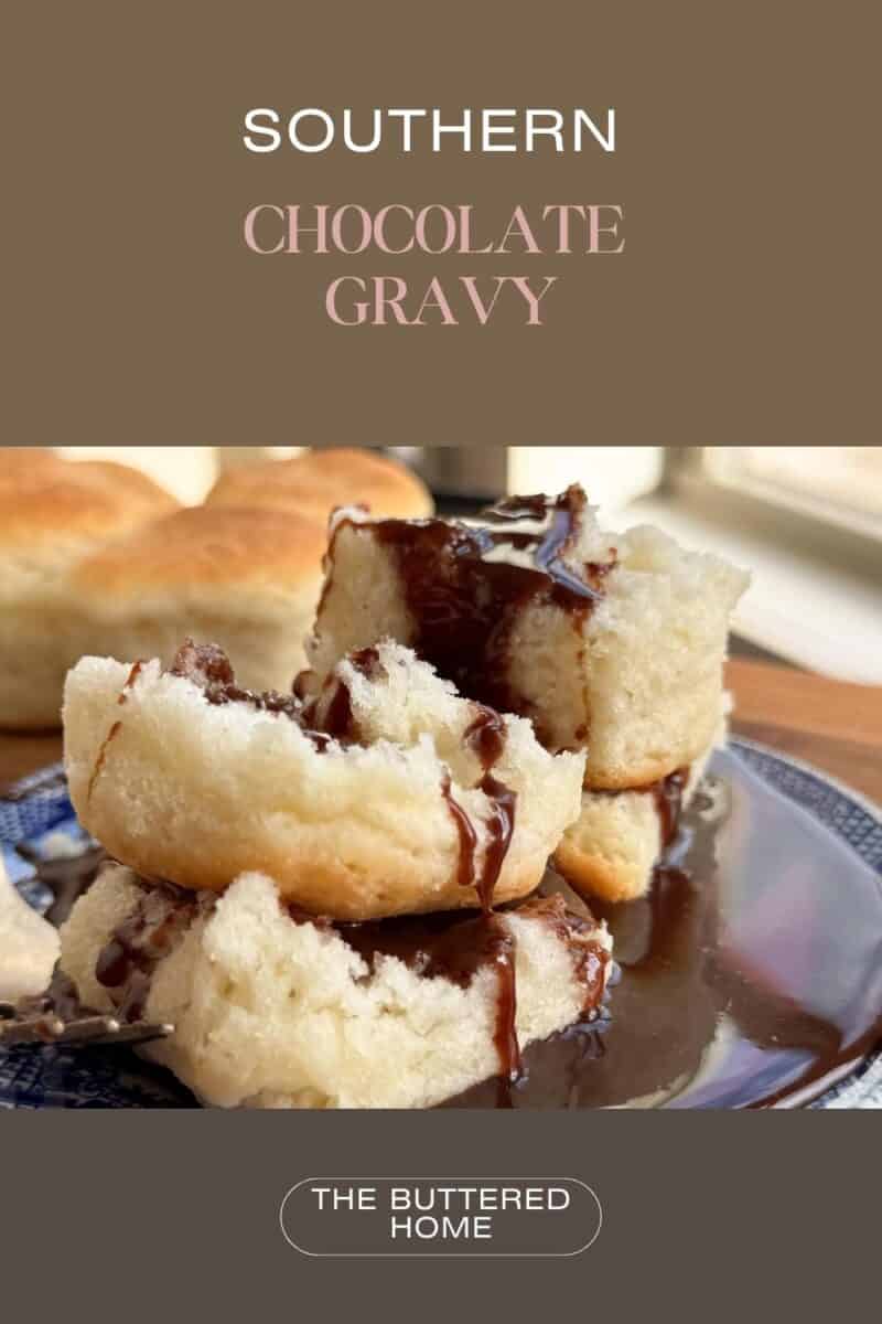 A close-up of a serving of chocolate gravy poured over a flaky biscuit, placed on a blue plate. In the background, more biscuits are visible on a wooden surface. The text "Southern Chocolate Gravy" and "The Buttered Home" is overlaid.