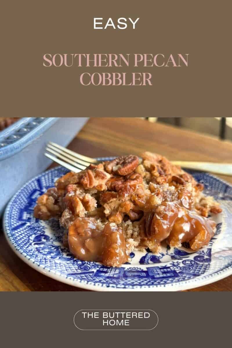 A slice of southern pecan cobbler on a blue and white patterned plate, topped with pecans and caramelized sauce. A fork is placed beside it on a wooden table. The text reads "Easy Southern Pecan Cobbler - The Buttered Home.