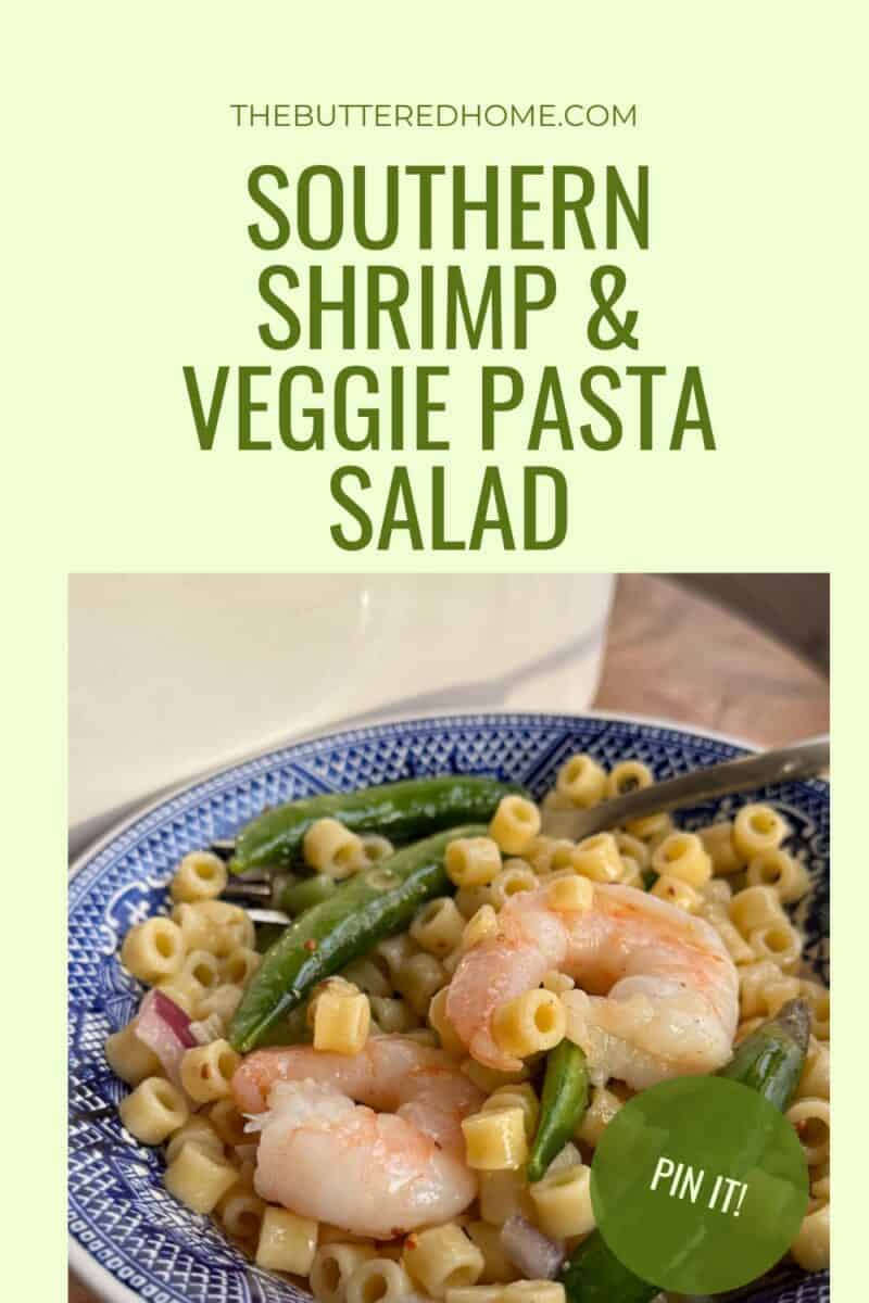 A blue and white plate contains pasta salad with shrimp, green beans, red onions, and peppers. The text above reads "THEBUTTEREDHOME.COM" and "SOUTHERN SHRIMP & VEGGIE PASTA SALAD" with a green circular "PIN IT!" button in the corner.