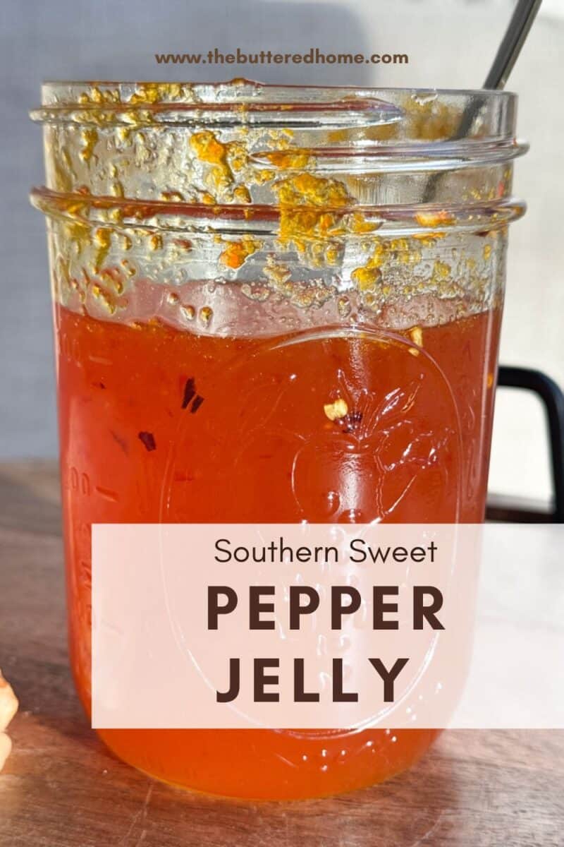A jar filled with Southern Sweet Pepper Jelly sits on a wooden surface. The jar is topped with a metal spoon, and remnants of jelly are visible near the rim. The text on the image reads "Southern Sweet Pepper Jelly" and a website URL is above.