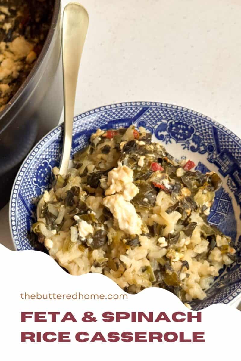 A blue and white bowl filled with a spinach and feta rice casserole sits on a white surface. A silver spoon is placed in the bowl. A partial view of a cooking pot with the same casserole appears on the left. The text reads "Feta & Spinach Rice Casserole.