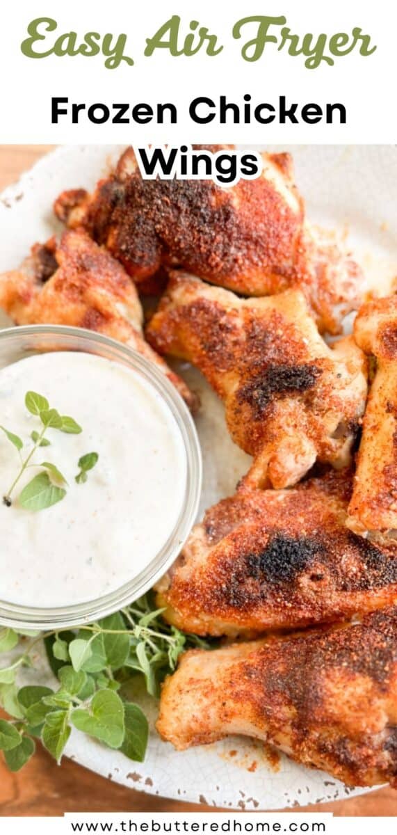 A plate of cooked chicken wings seasoned with spices sits next to a bowl of creamy dipping sauce and a sprig of fresh herbs; text above reads "Easy Air Fryer Frozen Chicken Wings.