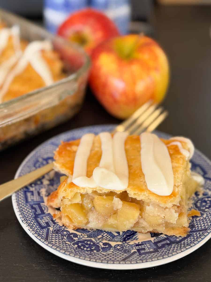 A plate of apple pie with a fork and apples.